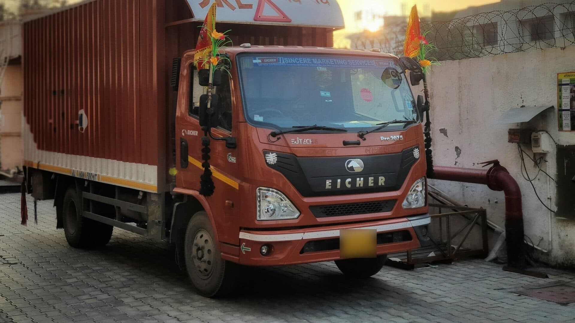 Cargo truck inside a walled factory yard, with the software's vehicle and number-plate detection boxes